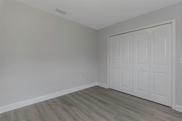 unfurnished bedroom featuring wood finished floors, baseboards, and a closet