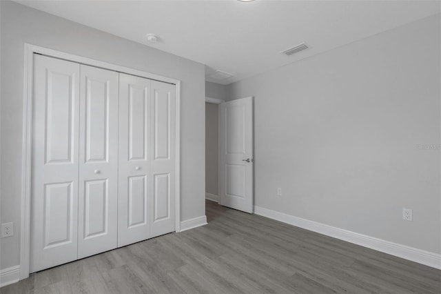 unfurnished bedroom with wood finished floors, a closet, and baseboards