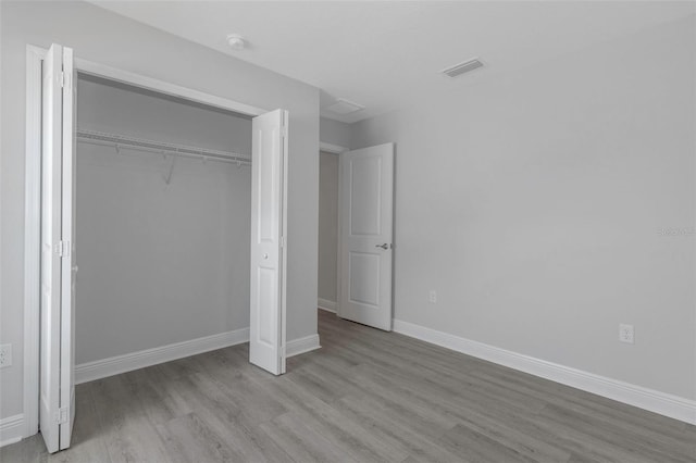 unfurnished bedroom featuring wood finished floors, baseboards, and a closet