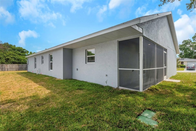 rear view of property featuring stucco siding and a sunroom