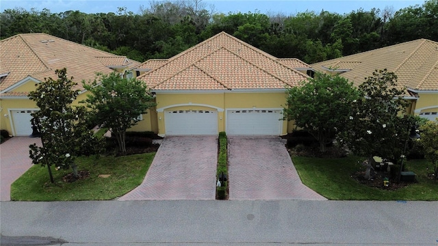 4837 Rainbow Race, New Port Richey, FL 34652 - view of front facade with a garage, decorative driveway, a tile roof, and stucco siding