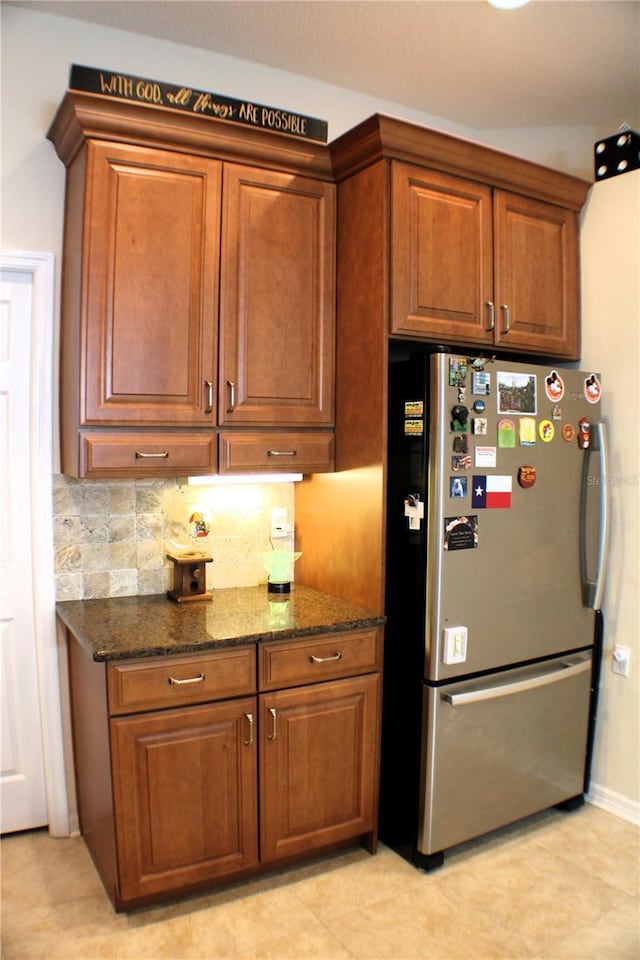 4837 Rainbow Race, New Port Richey, FL 34652 - kitchen with freestanding refrigerator, dark stone countertops, decorative backsplash, brown cabinetry, and baseboards