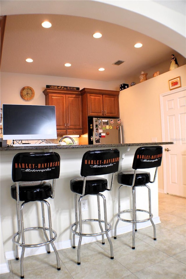 4837 Rainbow Race, New Port Richey, FL 34652 - kitchen with freestanding refrigerator, recessed lighting, brown cabinets, a breakfast bar, and light tile patterned flooring