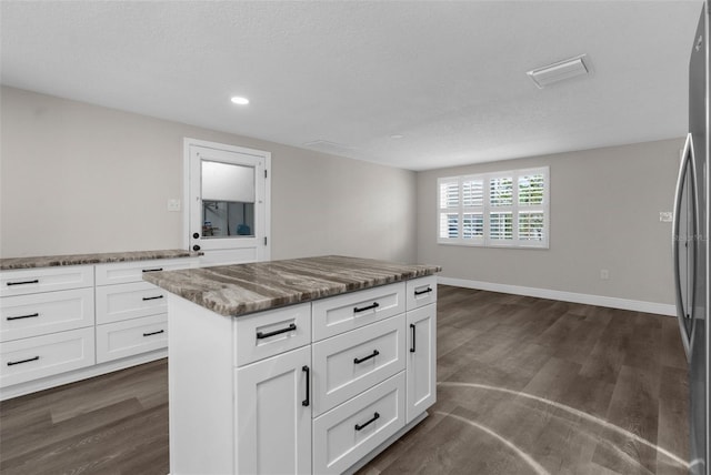 13411 Lisa Dr, Hudson, FL 34667 - kitchen with freestanding refrigerator, dark wood-style flooring, stone counters, recessed lighting, and white cabinetry