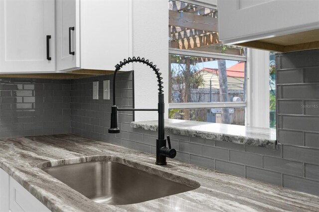 13411 Lisa Dr, Hudson, FL 34667 - kitchen view of a sink, tasteful backsplash, white cabinets, and light stone counters