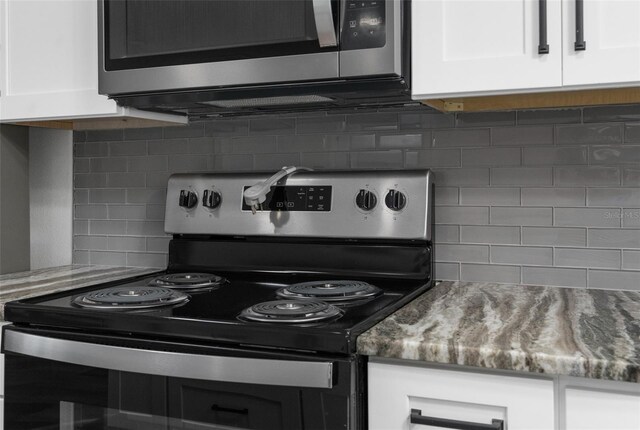 13411 Lisa Dr, Hudson, FL 34667 - kitchen featuring electric range oven, stainless steel microwave, tasteful backsplash, and white cabinets