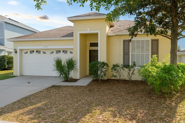 view of front of property featuring driveway, an attached garage, stucco siding, and roof with shingles