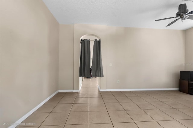unfurnished room featuring light tile patterned floors, a ceiling fan, and baseboards