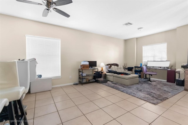 living room with light tile patterned floors, ceiling fan, and baseboards