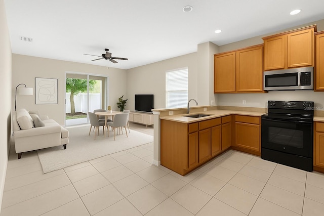 kitchen featuring stainless steel microwave, electric range, a sink, open floor plan, and light countertops
