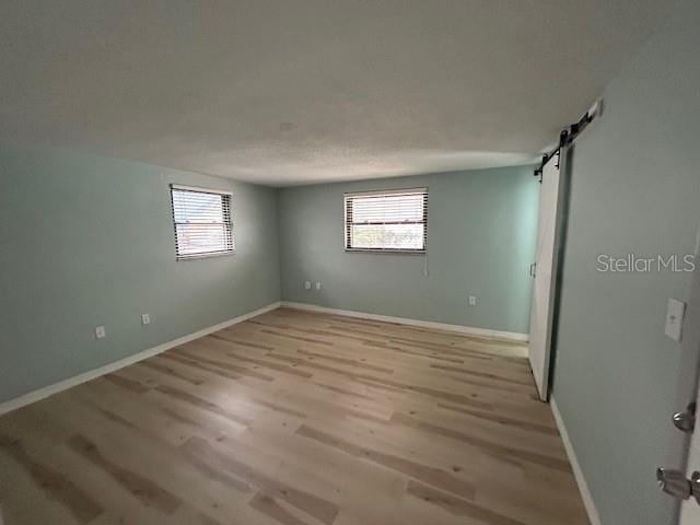 7331 Sandalwood Dr, Port Richey, FL 34668 - spare room featuring healthy amount of natural light, a barn door, light wood finished floors, and baseboards