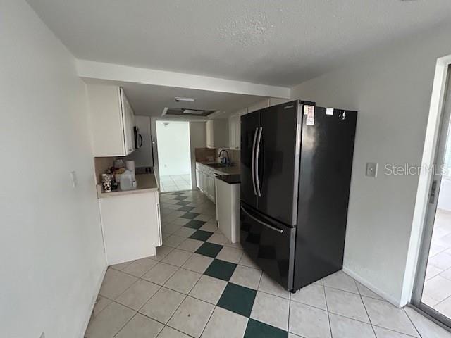 7331 Sandalwood Dr, Port Richey, FL 34668 - kitchen with freestanding refrigerator, a sink, white cabinetry, light tile patterned floors, and baseboards
