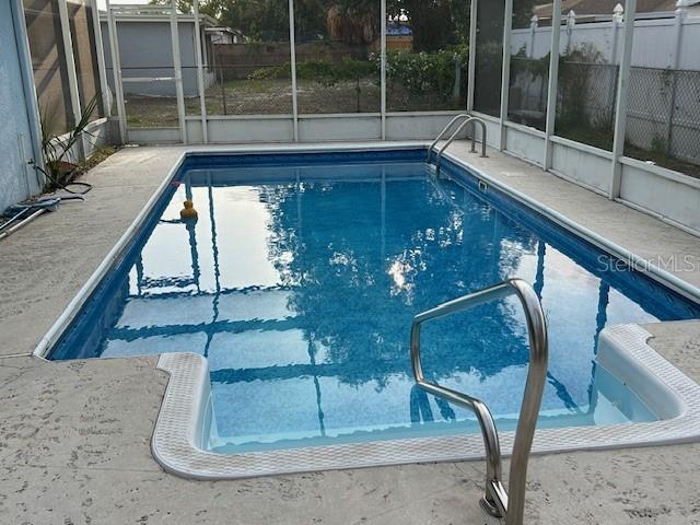 7331 Sandalwood Dr, Port Richey, FL 34668 - view of swimming pool with glass enclosure, a patio, and fence