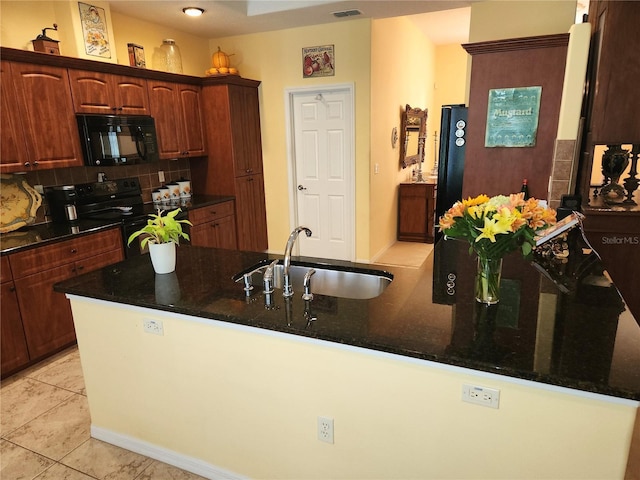 kitchen featuring black appliances, a sink, tasteful backsplash, dark stone countertops, and light tile patterned floors