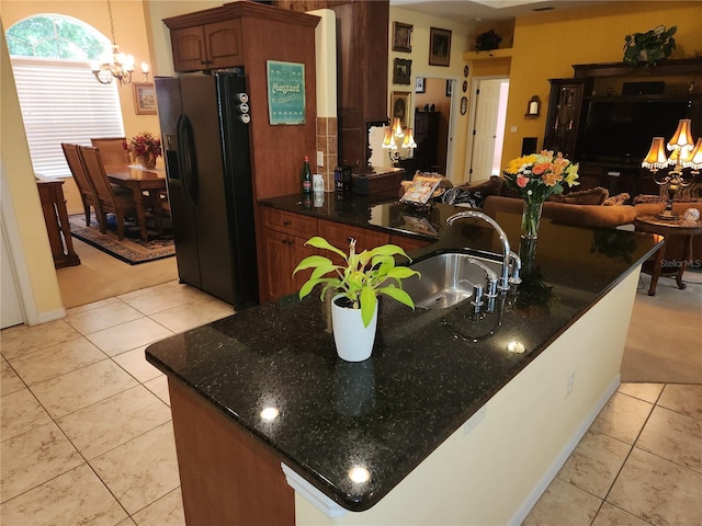 kitchen with black fridge with ice dispenser, a sink, a chandelier, light tile patterned floors, and open floor plan