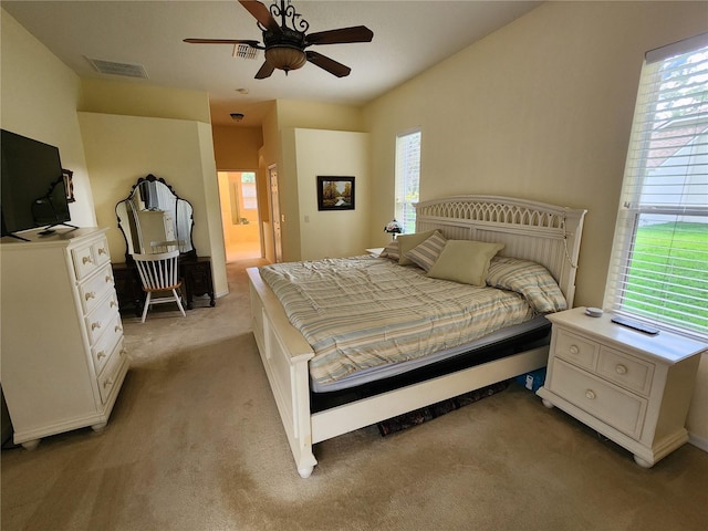 bedroom featuring light colored carpet, ensuite bath, and a ceiling fan