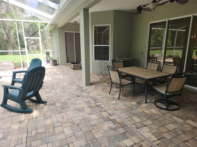 view of patio / terrace featuring ceiling fan, glass enclosure, and outdoor dining space