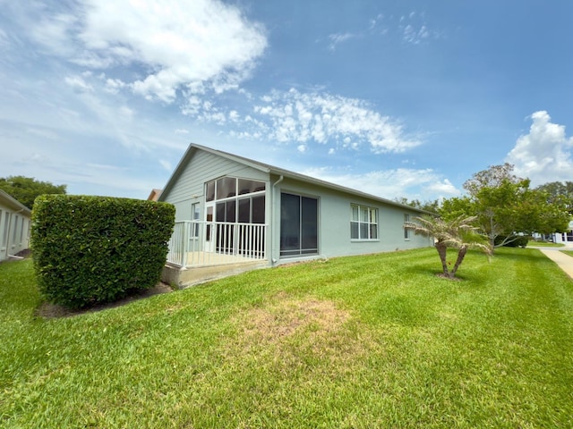 18109 Webster Grove Dr, Hudson, FL 34667 - rear view of property featuring a sunroom, a lawn, and stucco siding