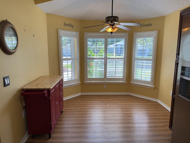 18109 Webster Grove Dr, Hudson, FL 34667 - unfurnished dining area featuring wood finished floors, plenty of natural light, a ceiling fan, a textured ceiling, and baseboards