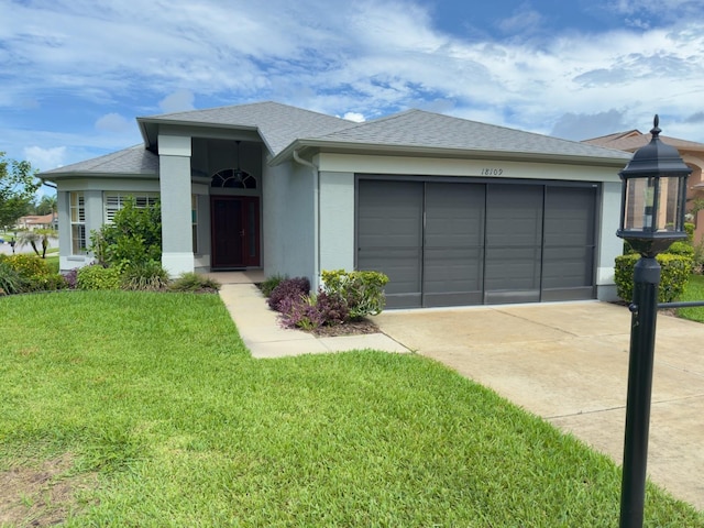18109 Webster Grove Dr, Hudson, FL 34667 - view of front of property with driveway, an attached garage, a front lawn, stucco siding, and roof with shingles