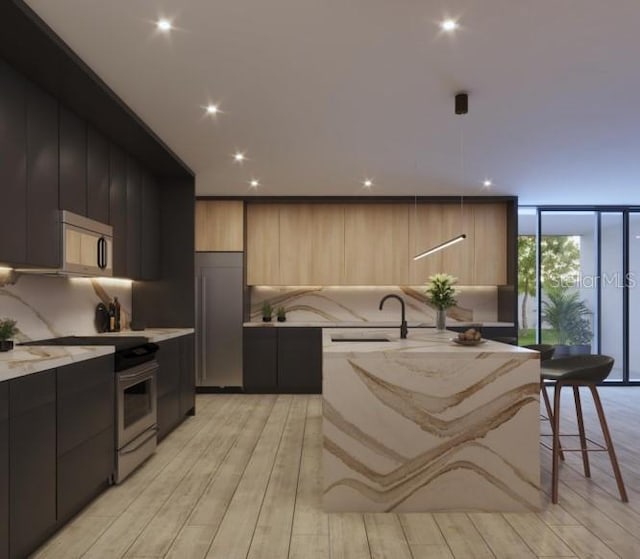 kitchen featuring modern cabinets, stainless steel appliances, a sink, an island with sink, and backsplash
