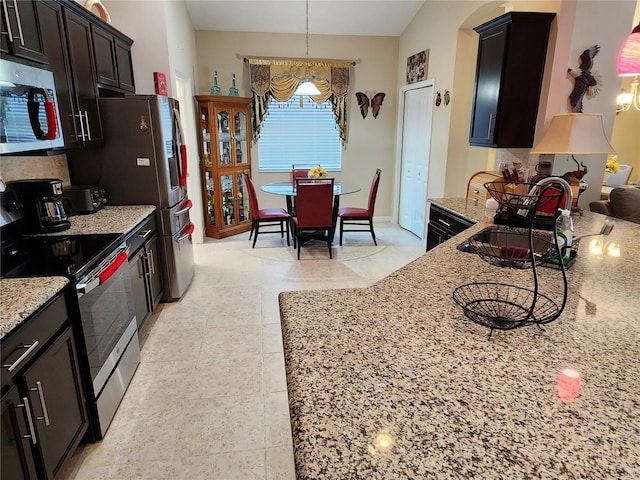 kitchen with appliances with stainless steel finishes, light stone countertops, tasteful backsplash, and a sink