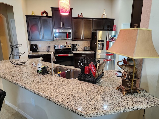 kitchen featuring stainless steel appliances, arched walkways, light stone countertops, and backsplash