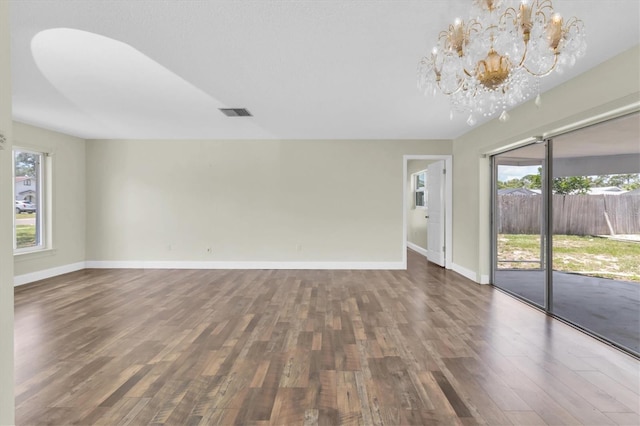 1402 Tallahassee Dr, Tarpon Springs, FL 34689 - unfurnished living room with a chandelier, wood finished floors, and baseboards