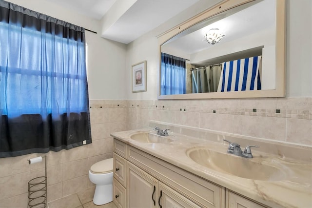1402 Tallahassee Dr, Tarpon Springs, FL 34689 - full bath featuring tile walls, toilet, tile patterned flooring, double vanity, and a wainscoted wall