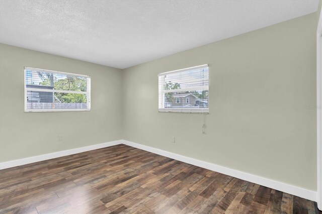 1402 Tallahassee Dr, Tarpon Springs, FL 34689 - empty room featuring healthy amount of natural light, baseboards, dark wood-style flooring, and a textured ceiling