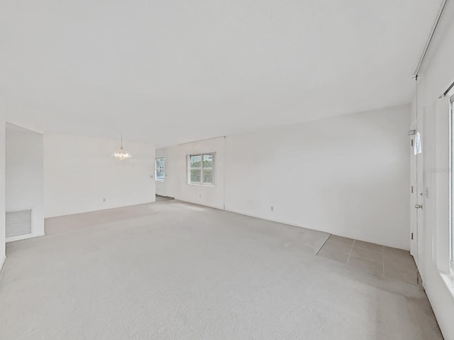 spare room with a chandelier and light carpet