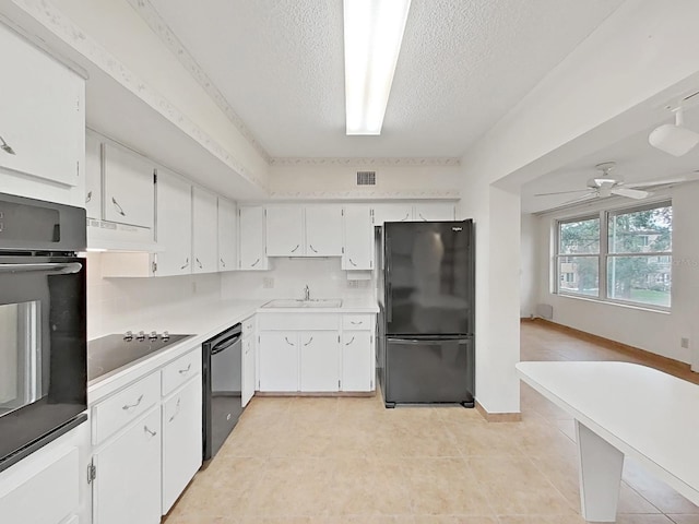 kitchen featuring black appliances, a sink, a textured ceiling, under cabinet range hood, and white cabinetry