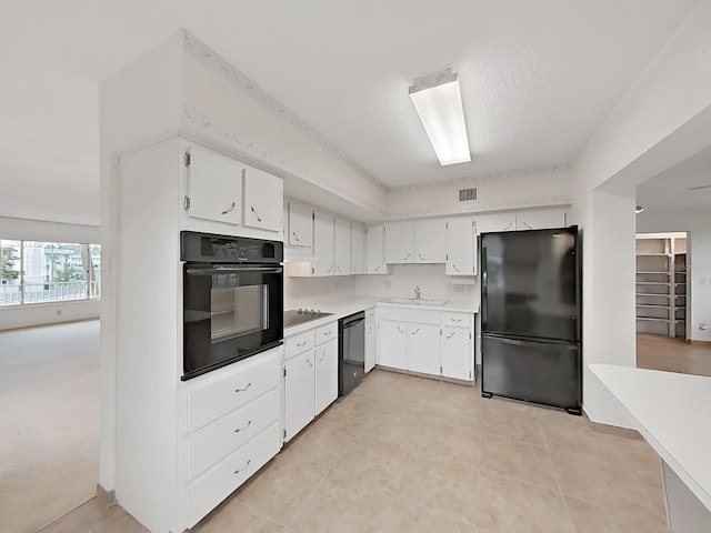 kitchen featuring black appliances, light countertops, a sink, white cabinetry, and light tile patterned floors