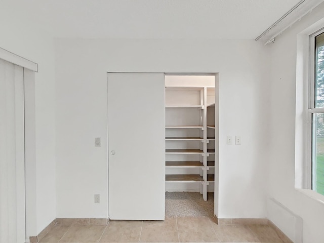 unfurnished bedroom with a closet, light tile patterned floors, and a walk in closet