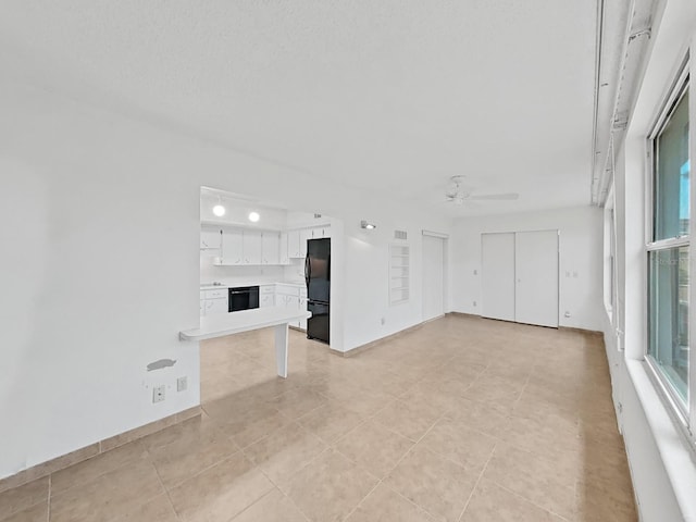 unfurnished living room with a ceiling fan, light tile patterned floors, and healthy amount of natural light