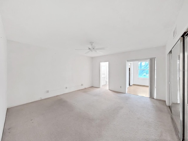 empty room featuring a ceiling fan and light carpet