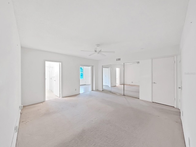 unfurnished bedroom featuring light carpet, a ceiling fan, and connected bathroom