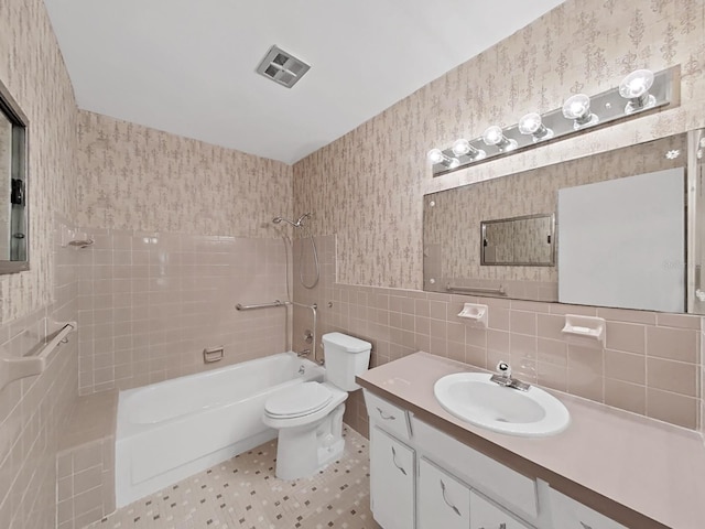 full bath featuring tile walls, toilet, bathing tub / shower combination, vanity, and wallpapered walls