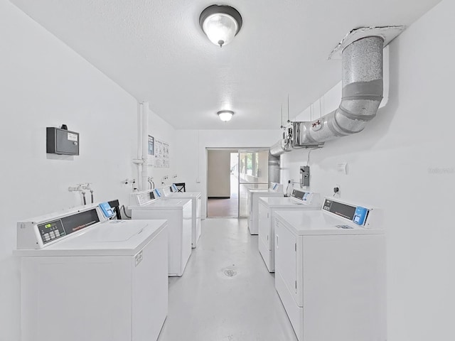 communal laundry room with washing machine and dryer and a textured ceiling
