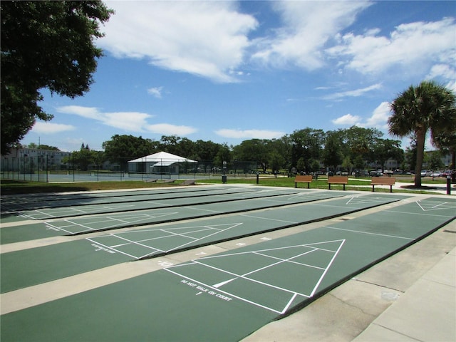 view of property's community featuring fence, shuffleboard, and a tennis court