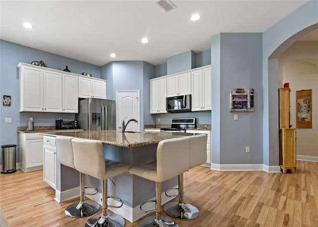 11401 Quiet Forest Dr, Tampa, FL 33635 - kitchen featuring stainless steel appliances, light wood-type flooring, a kitchen bar, baseboards, and white cabinets