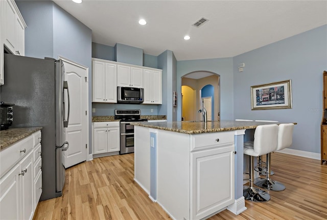 11401 Quiet Forest Dr, Tampa, FL 33635 - kitchen with stainless steel appliances, light wood-style flooring, arched walkways, a kitchen island with sink, and recessed lighting