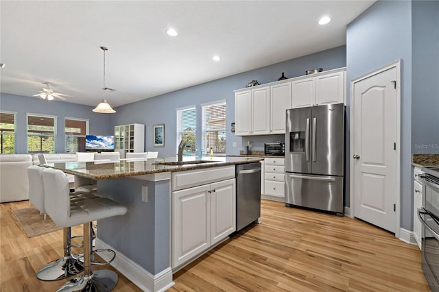 11401 Quiet Forest Dr, Tampa, FL 33635 - kitchen featuring stainless steel appliances, light wood-style floors, a sink, open floor plan, and white cabinetry