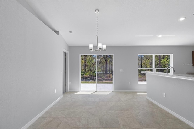 unfurnished dining area with healthy amount of natural light, a chandelier, baseboards, recessed lighting, and a sink