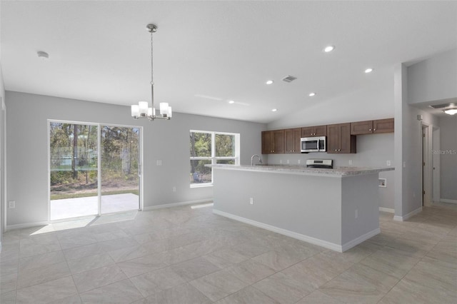 kitchen with appliances with stainless steel finishes, a chandelier, pendant lighting, an island with sink, and baseboards