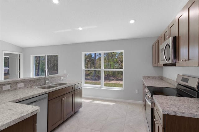 kitchen with appliances with stainless steel finishes, a sink, light countertops, recessed lighting, and baseboards
