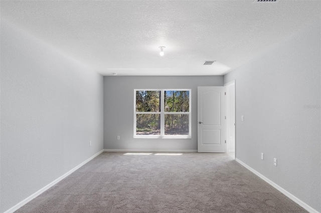 carpeted spare room with a textured ceiling and baseboards