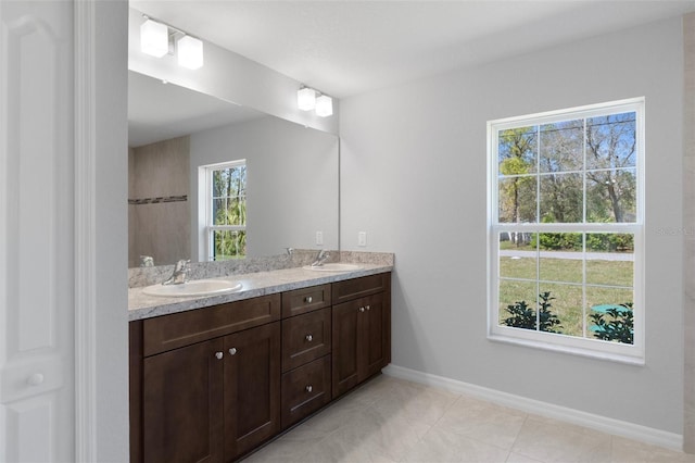 bathroom with double vanity, baseboards, and tile patterned flooring