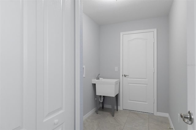 laundry area with light tile patterned floors and baseboards