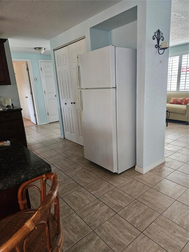 6339 Delaware Ave, New Port Richey, FL 34653 - kitchen featuring freestanding refrigerator, a textured ceiling, light tile patterned floors, and a textured wall